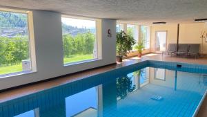 a swimming pool with a blue tile floor and windows at Pension Thalerhof in Rifiano