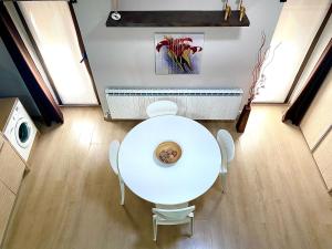 une table et des chaises blanches dans une pièce avec radiateur dans l'établissement Apartamentos Lorione, à Olite