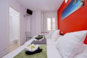 a bedroom with two beds and a red wall at Barcelona City North Hostal in Barcelona