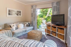 a living room with couches and a flat screen tv at Aloe Cottage at Ibis House in Cape Town