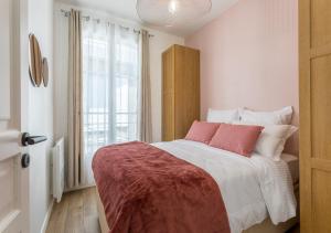- une chambre avec un lit doté d'oreillers roses et blancs dans l'établissement Maison Morny, à Deauville