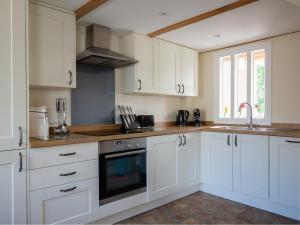 Una cocina con gabinetes blancos y un fregadero. en Oliver Cromwell, en Winchcombe