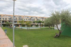 a park with a building and a tree in the grass at Panorámica Golfmar c/ Generalitat in Sant Jordi