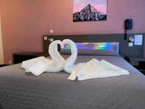 Dos toallas de cisne se hacen para parecer cisnes en una cama en Aero Hotel en Issy-les-Moulineaux