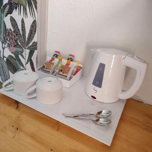 una macchinetta del caffè e tazze su un bancone con cucchiai di Le monte rosso a Porto Ota