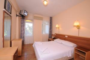 a bedroom with a white bed and a television at SERİN HOTEL in Marmaris