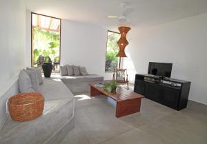 ein Wohnzimmer mit einem Sofa und einem TV in der Unterkunft Pousada Cheiro Verde in Arraial d'Ajuda