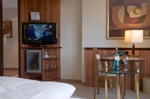 um quarto de hotel com uma televisão, uma mesa e uma cama em Ringhotel Katharinen Hof em Unna