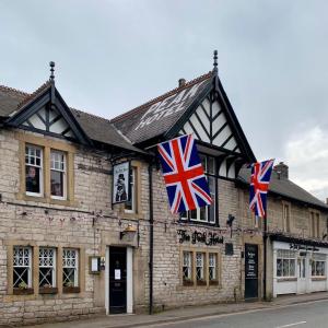 Duas bandeiras britânicas estão penduradas do lado de fora de um edifício. em Peak Hotel Castleton em Castleton
