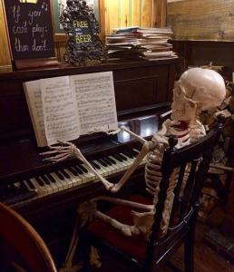 a skeleton sitting on a chair in front of a piano at Peak Hotel Castleton in Castleton