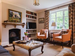 - un salon avec une cheminée, une table et des chaises dans l'établissement Sudeley Castle Guest Cottage, à Winchcombe