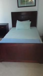 a large bed with a wooden headboard and a night stand at 1B studio 2beds air conditioned basement114 green beach in El Alamein