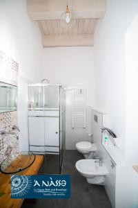 Baño blanco con 2 aseos y lavamanos en Bed & breakfast La Nassa, en Taranto