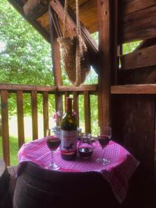 uma mesa com uma garrafa de vinho e dois copos em Etno kuća Milidrag em Foca