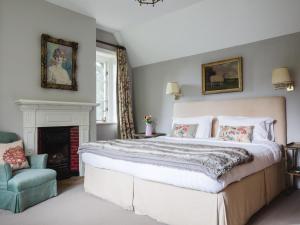 - une chambre avec un grand lit et une cheminée dans l'établissement Sudeley Castle Guest Cottage, à Winchcombe