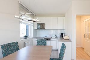 a kitchen with a wooden table and blue chairs at Domizil Strandläufer in Wenningstedt