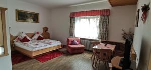 1 dormitorio con 1 cama, 1 silla y 1 mesa en Gästehaus-Pension Keiss, en Hopferau