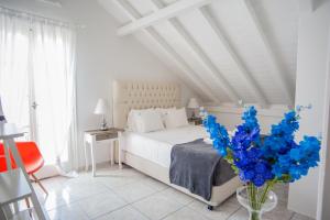 a white bedroom with a bed and blue flowers in a vase at Angel Apartment in Fiskardo