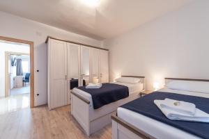 a white bedroom with two beds and a mirror at Holiday House Lavanda in Vrsi