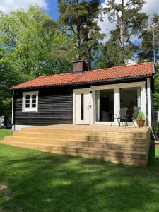 a small house with a wooden deck in a yard at Skogshöjda in Tjörnarp