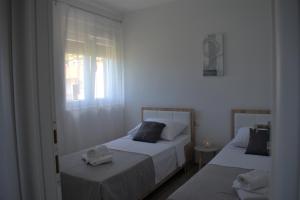 2 bedden in een witte kamer met een raam bij Apartments Rena in Šibenik