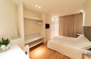 チヴィタノーヴァ・マルケにあるHotel Country House La Radiceの白いベッドとテレビが備わるホテルルームです。