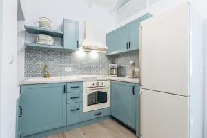 una cucina con armadi blu e frigorifero bianco di Suite Christina a Sými