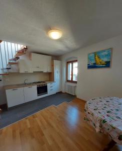 a kitchen with white cabinets and a bed in a room at L'angolo di Giulia in Castelletto di Brenzone