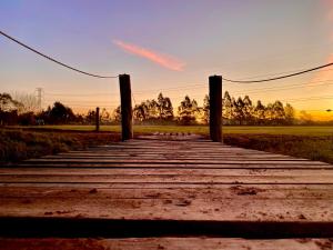 a wooden boardwalk leading to a field at sunset at LA GUAPEADA POLO PILAR in Pilar