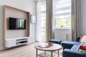 a living room with a tv and a blue couch at Sanhaus Apartments - Apartament Mera z parkingiem i klimatyzacją in Sopot
