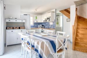 - une cuisine avec des placards blancs, une table et des chaises dans l'établissement Maison Marceane, à Sainte-Marie de Ré