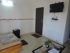 a living room with a table and a tv on the wall at HAPPY WELCOME Biétry 3 - MARCORY ZONE 4 in Abidjan
