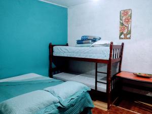 two bunk beds in a room with blue walls at Pertinho prahia toninhas in Ubatuba