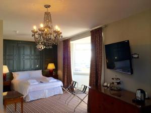 a bedroom with a bed and a television and a chandelier at Seaspray Rooms in Bexhill