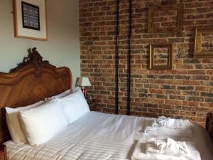 a bedroom with a bed with a brick wall at Seaspray Rooms in Bexhill