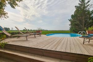 una terraza de madera con sillas y una piscina en Mas des Prépresses - la Maison des vendangeurs en Beaucaire