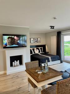 a living room with a bed and a tv on a wall at Strandhus in Rantum