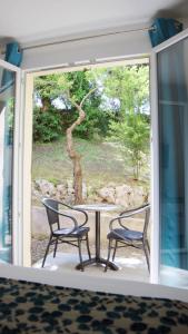 2 sillas y una mesa frente a una ventana en Le Moulin du Verdon en Gréoux-les-Bains