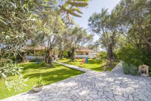 un patio trasero con un camino de piedra y árboles en Villa Hector, en Lefkada