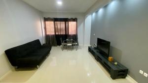 a living room with a black couch and a television at T1 Família Luz in Mindelo