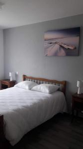 a bedroom with a white bed with a painting on the wall at Le Fair Play in Léon