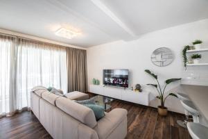sala de estar blanca con sofá y TV en Electra Residence - Luxury Central Beachview Apartment, en Marsalforn
