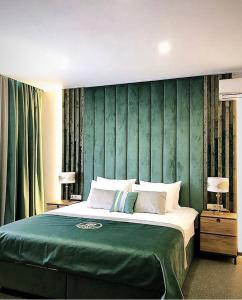 a bedroom with a large bed with a green headboard at Green Garden Hotel in Kol'chugino