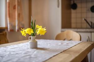 un jarrón con flores amarillas sentado en una mesa en Ferienwohnung Kirchblick Gasser, en Terento