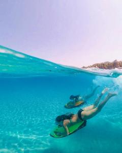 a woman laying on a surfboard in the water at Alexander the Great Beach Hotel in Kriopigi