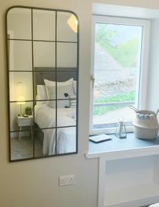 a mirror in a bedroom with a bed and a window at Orkney Staycations - Thorvald in Finstown