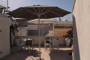 an umbrella on a balcony with tables and chairs at B&B Salentus in Gallipoli