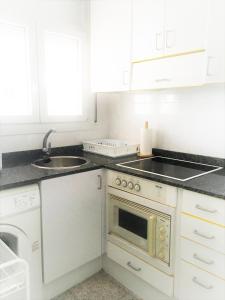 een witte keuken met een wastafel en een magnetron bij Apartament a la Costa Brava l'Estartit - MyAnna in L'Estartit