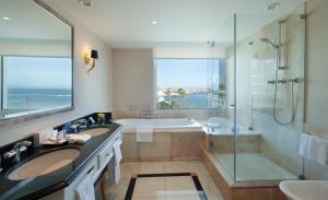 a bathroom with two sinks and a shower and a tub at Hotel Cascais Miragem Health & Spa in Cascais