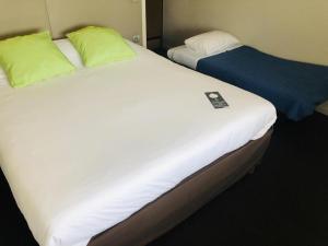 two twin beds in a hotel room with at Campanile Pont-à-Mousson in Pont-à-Mousson